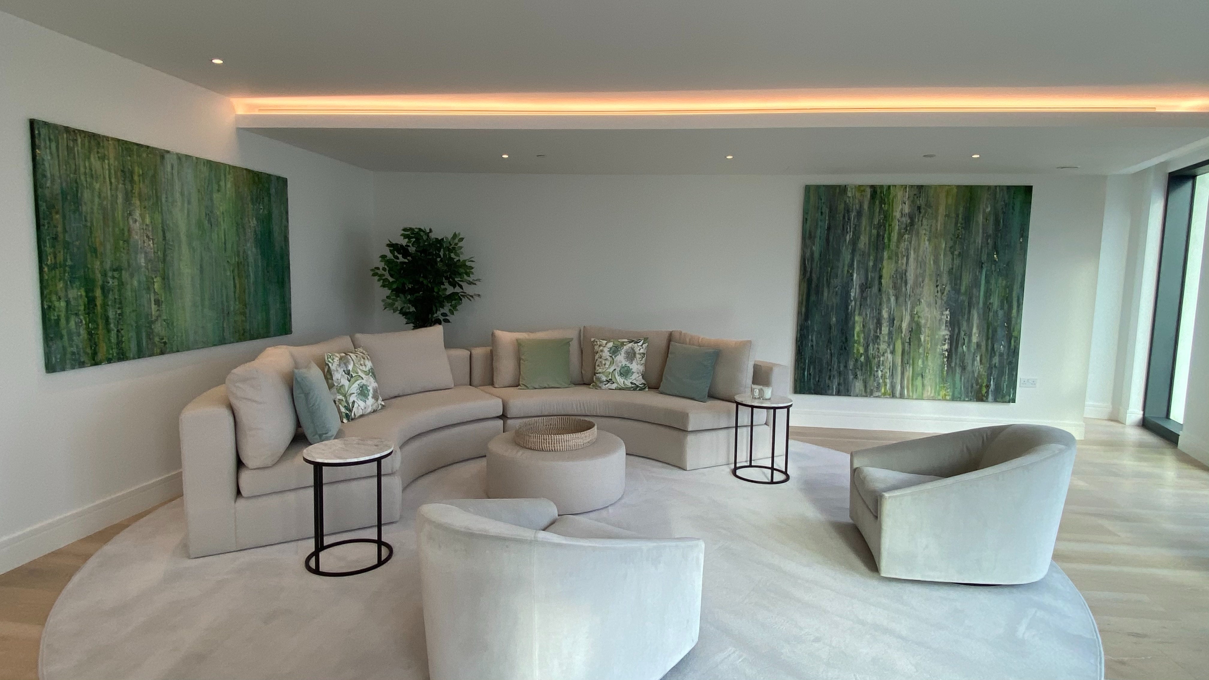 A large spacious living room with a large grey rug and green artwork on the walls
